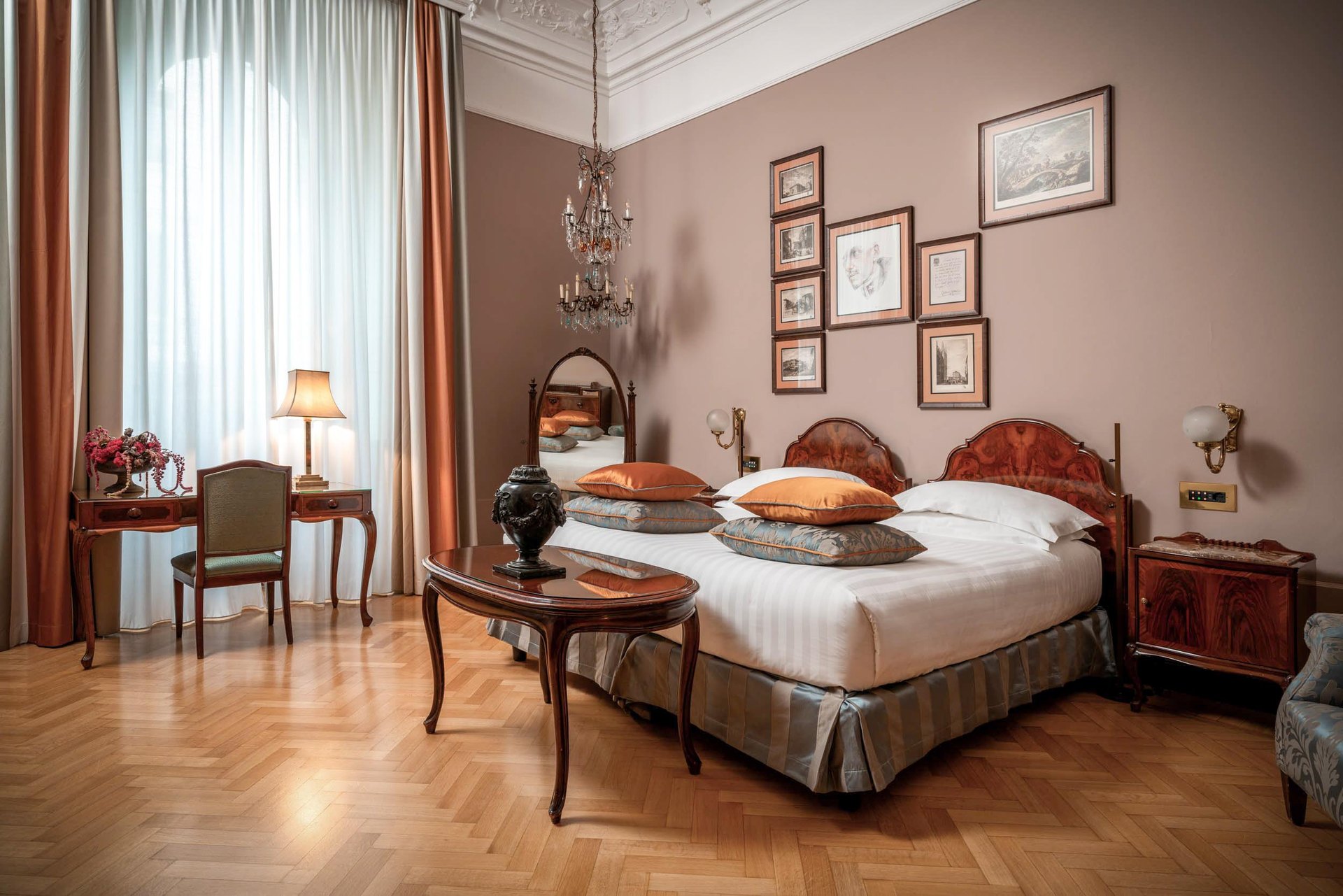 A bedroom at the Grand Hotel et de Milan, with parquet floor, antique furniture and framed prints