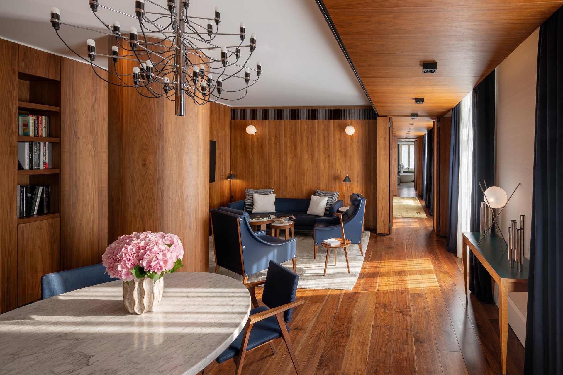 A suite living room at Mandarin Oriental, Milan, in walnut panelling with a Sputnik chandelier and blue armchairs