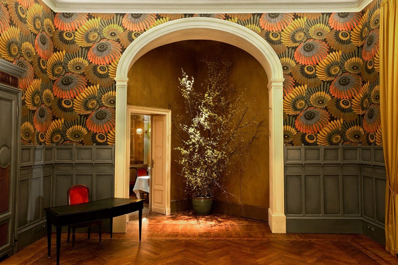 A salon at Cracco in Galleria, with flower-patterned wallpaper, panelling and an arched alcove