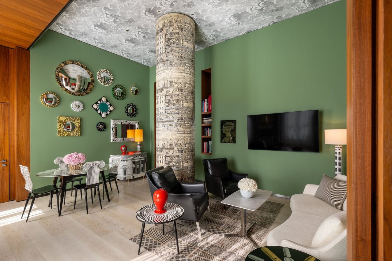 The Fornasetti Suite at Mandarin Oriental, Milan, with a column and ceiling printed by Fornasetti and green walls hung with mirrors and plates